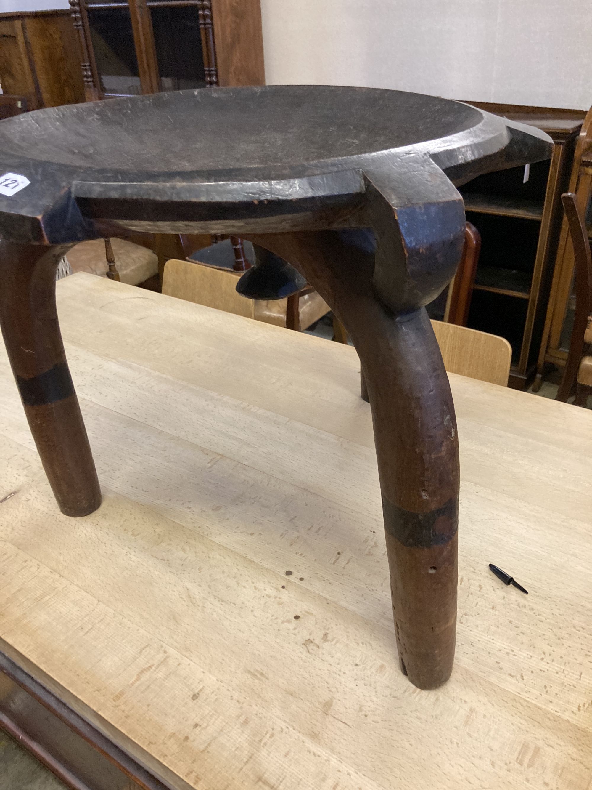 An African carved hardwood bowl seat three legged stool, diameter 60cm, height 52cm